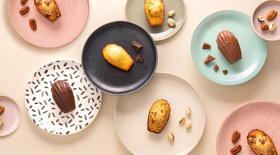 Assortiment de différentes madeleines disposé dans des assiettes colorées