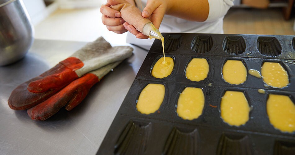 Pâtissier qui remplit son moule à madeleines 